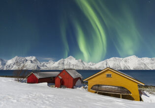 Traditional fisherman cottages in the snowy landscape under northern lights (aurora borealis), Lyngen Alps, Troms, Nord-Norge, Norway, Scandinavia