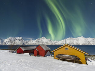 Traditional fisherman cottages in the snowy landscape under northern lights (aurora borealis), Lyngen Alps, Troms, Nord-Norge, Norway, Scandinavia