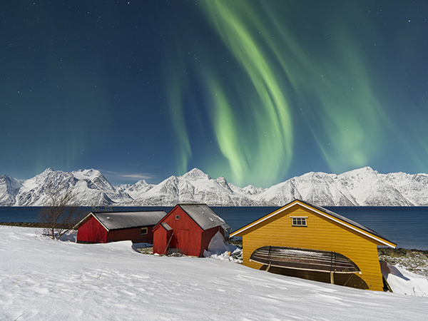 Traditional fisherman cottages in the snowy landscape under northern lights (aurora borealis), Lyngen Alps, Troms, Nord-Norge, Norway, Scandinavia