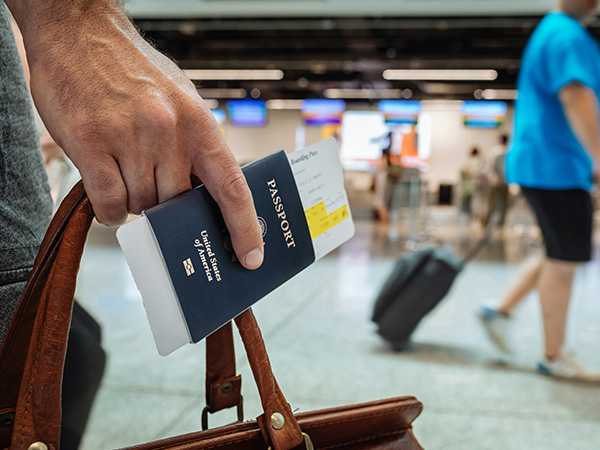 man holding bag and passport at airport