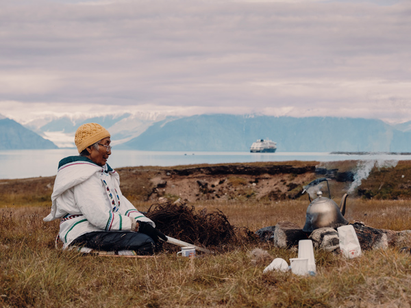 Local woman sits in the grasslands of Gjoa Haven / Uqsuqtuuq