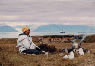 Local woman sits in the grasslands of Gjoa Haven / Uqsuqtuuq