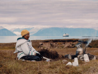 Local woman sits in the grasslands of Gjoa Haven / Uqsuqtuuq