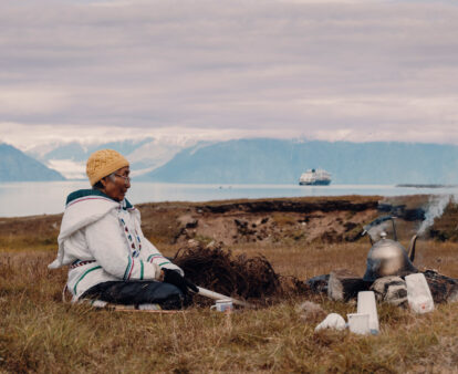 Local woman sits in the grasslands of Gjoa Haven / Uqsuqtuuq