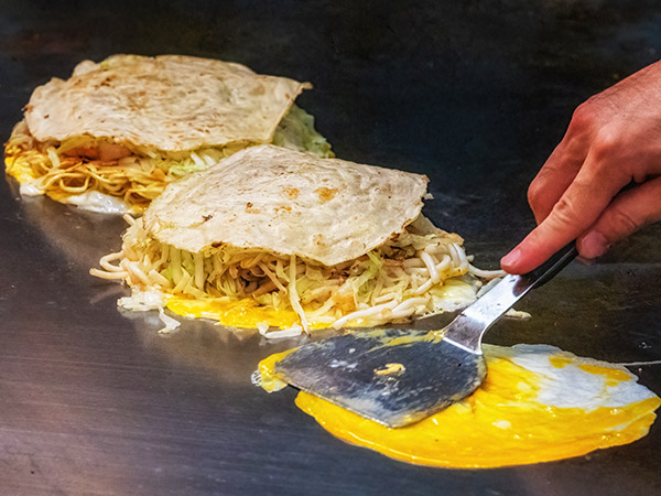 A chef makes Hiroshima style Okonomiyaki in Hiroshima, Japan